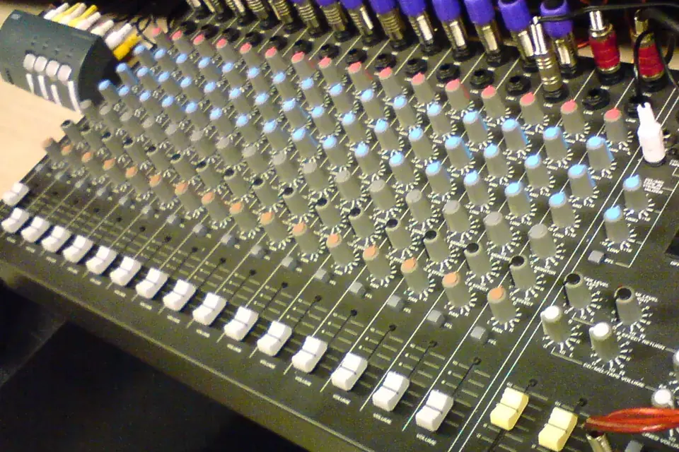 Gros plan sur une petite table de mixage analogique avec ses rangées de boutons colorés et ses curseurs