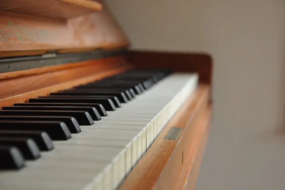 Gros plan oblique sur le clavier d'un piano droit en bois, touches blanches et noires